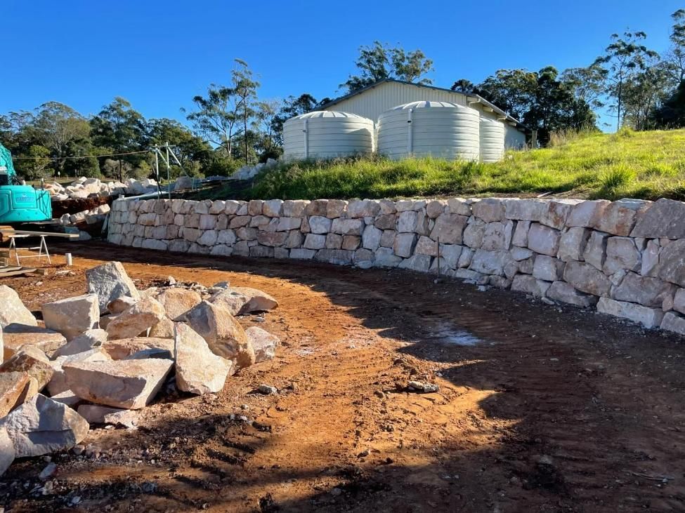 A Stone Wall Is Being Built in A Dirt Field — Webster Rock Walls In Ilkley, QLD