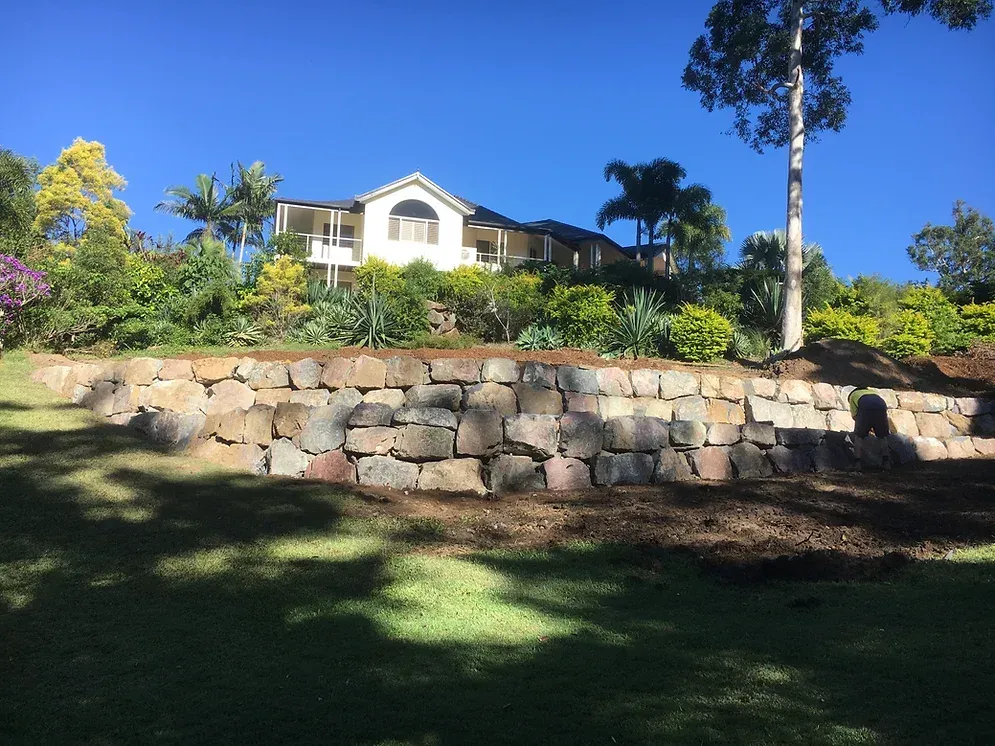 A Large House Is Sitting on Top of A Hill Next to A Stone Wall — Webster Rock Walls In Ilkley, QLD