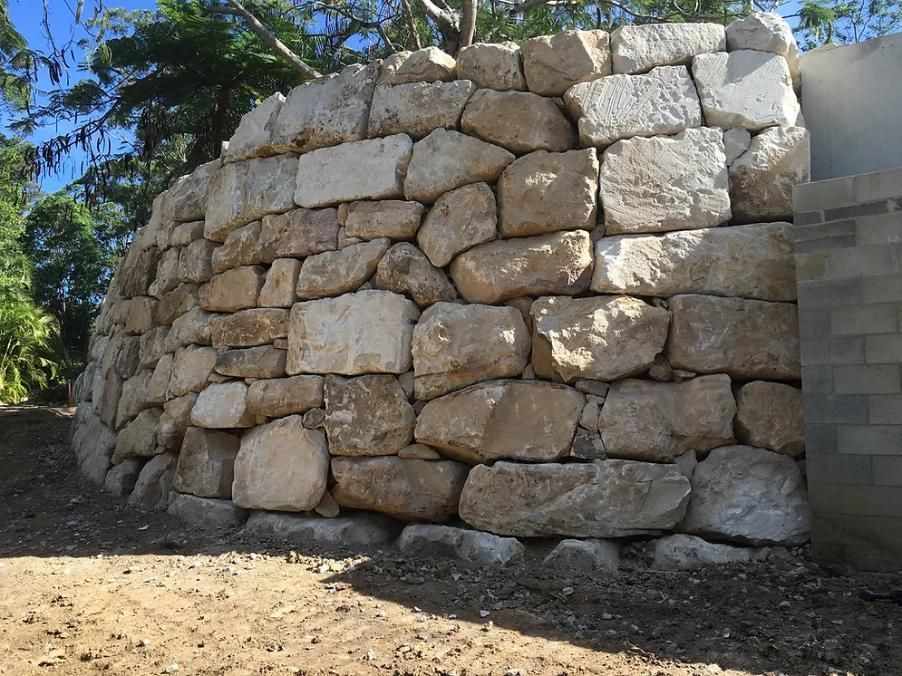 A Large Stone Wall Is Sitting on Top of A Dirt Field — Webster Rock Walls In Ilkley, QLD