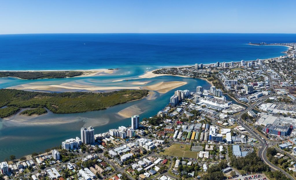An aerial view of a city with a river running through it and the ocean in the background. — Webster Rock Walls In Sunshine Coast, QLD