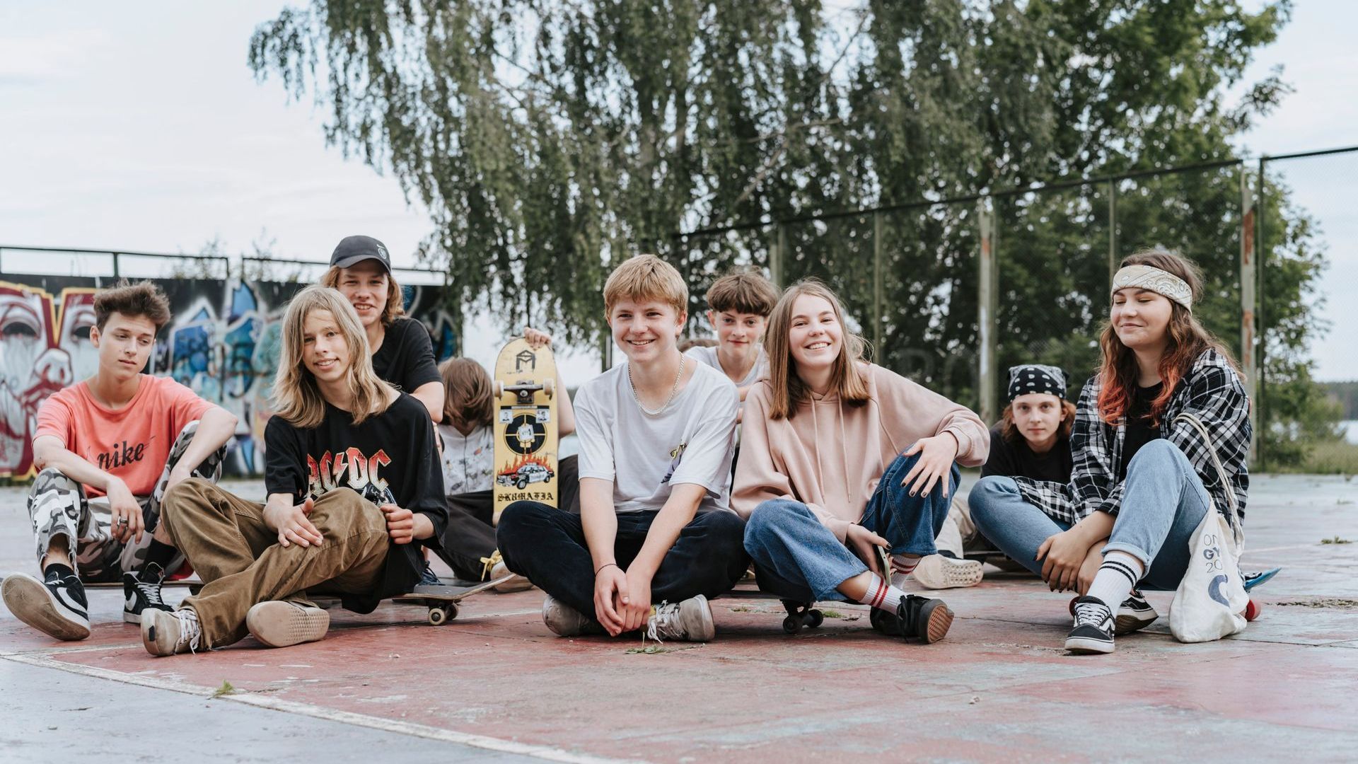 a group of young people are sitting on skateboards on a skate park .