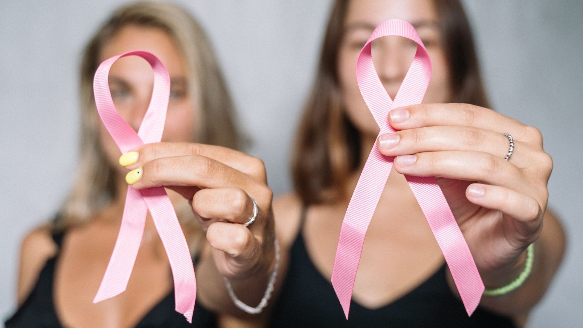 Two women holding pink ribbons