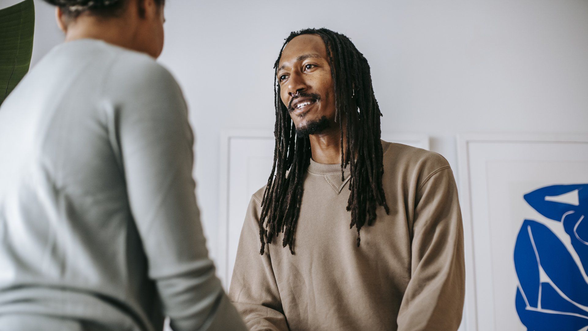 a man with dreadlocks is shaking hands with a woman .