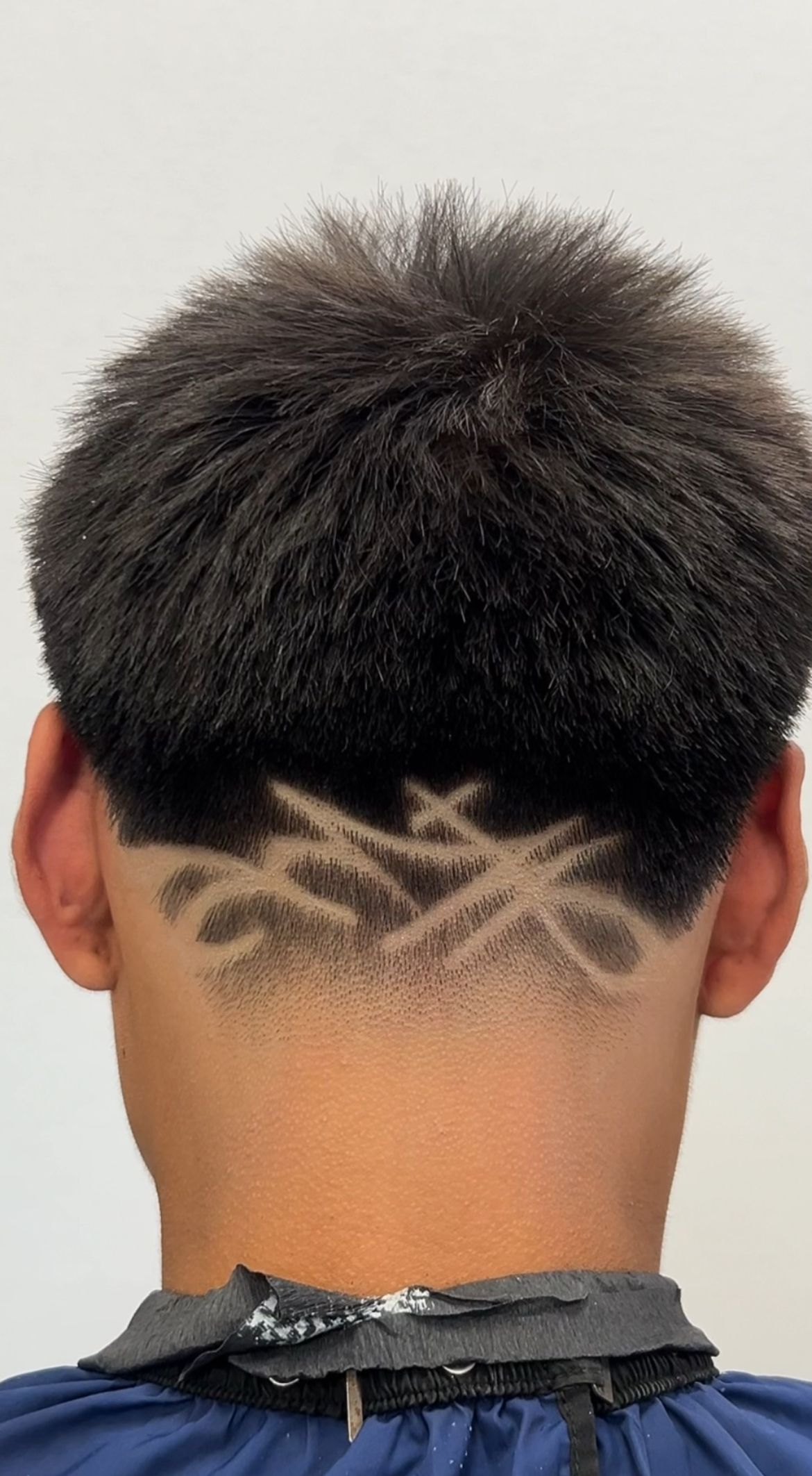 Person's nape with a fade haircut and a design shaved into the lower part.