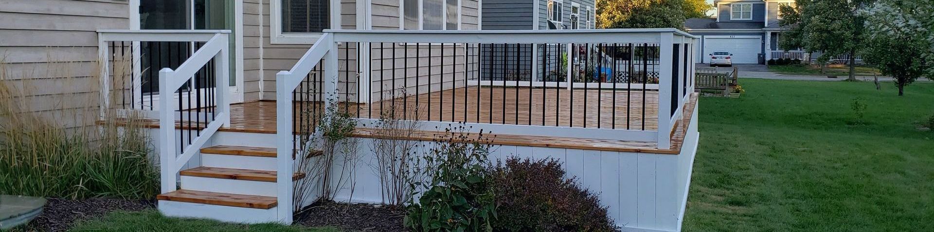 A deck with stairs leading up to it is in front of a house.