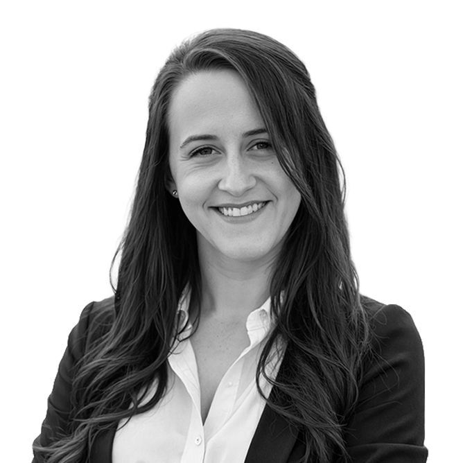 Woman with long dark hair smiles, wearing a blazer and white collared shirt.