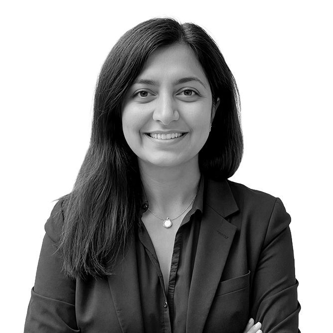 Woman with dark hair smiles, wearing a blazer and collared shirt.