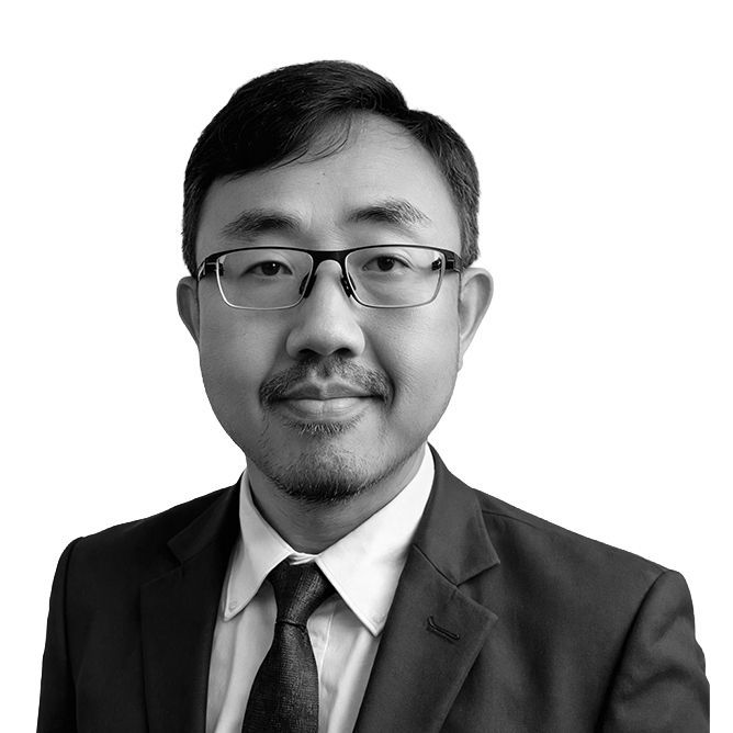 Man in glasses and suit, looking at the camera, neutral expression.