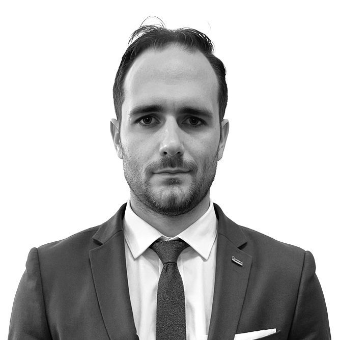 Man in a suit and tie, looking directly at the camera. Black and white, head and shoulders.