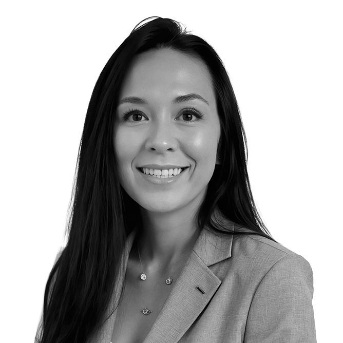 Woman with long dark hair smiles, wearing a blazer.