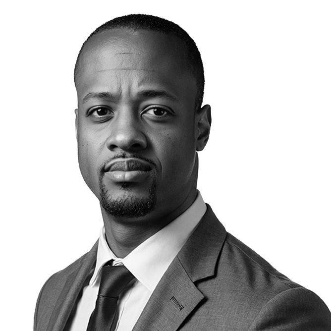 A man in a suit looks directly at the camera with a serious expression.