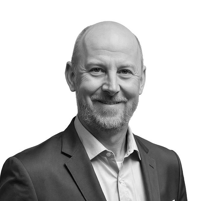 A smiling man with a shaved head and beard, wearing a suit jacket and dress shirt.