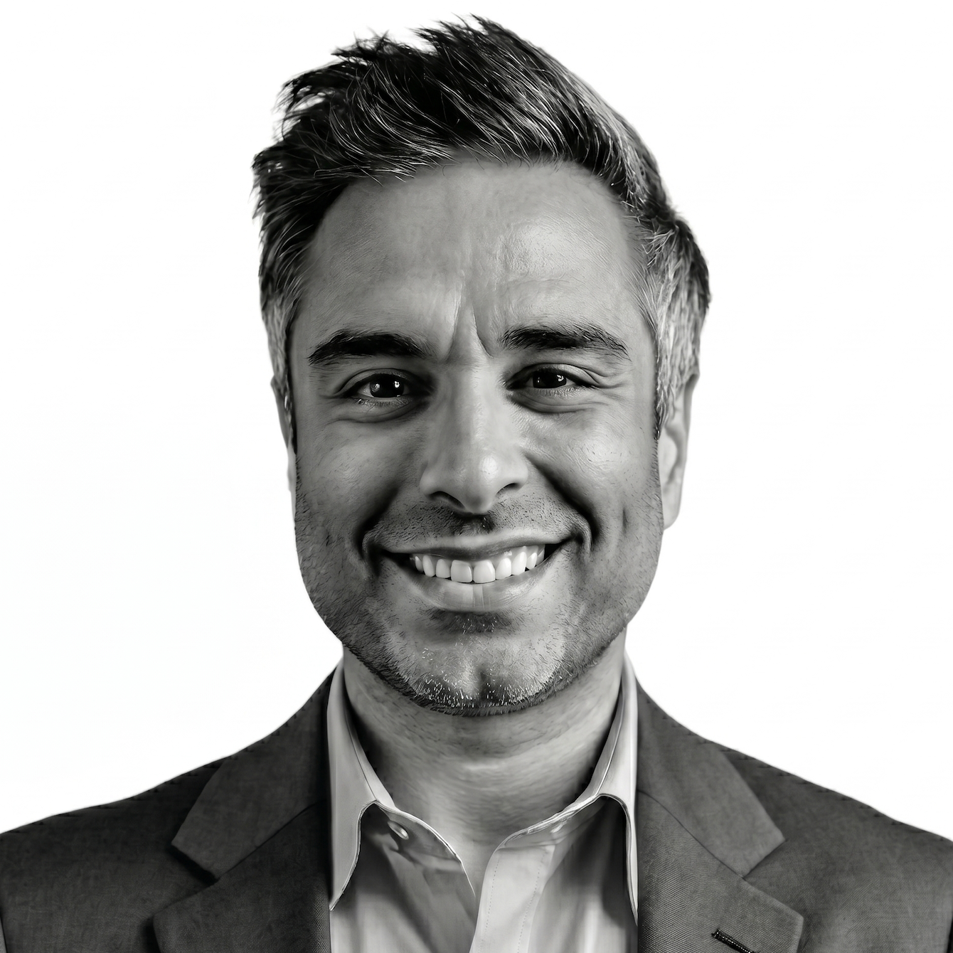 Man smiling, wearing a sweater and collared shirt. Black and white photo.