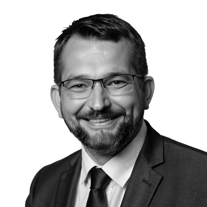 Man wearing glasses and a suit, smiling broadly.