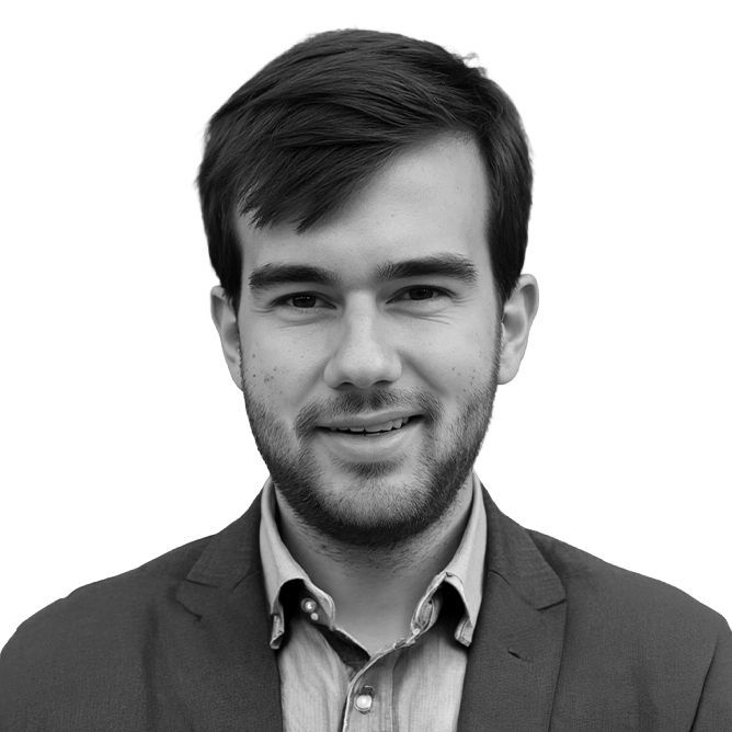 Man wearing a blazer and button-down shirt smiles at the camera. Black and white photo.