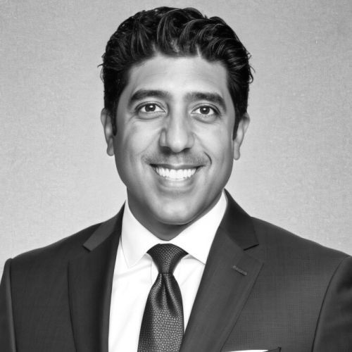 Man in a suit smiles at the camera, headshot.