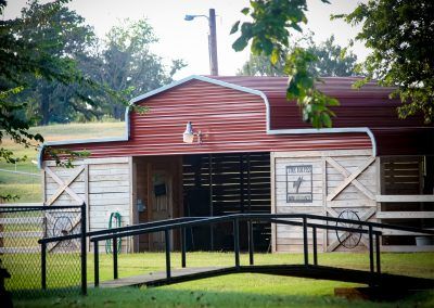 A red and white barn with a ramp leading to it.