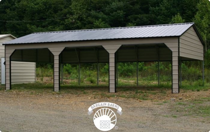 A large metal building with a black roof is sitting in the middle of a dirt field.
