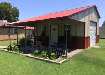 A small house with a porch and a red roof