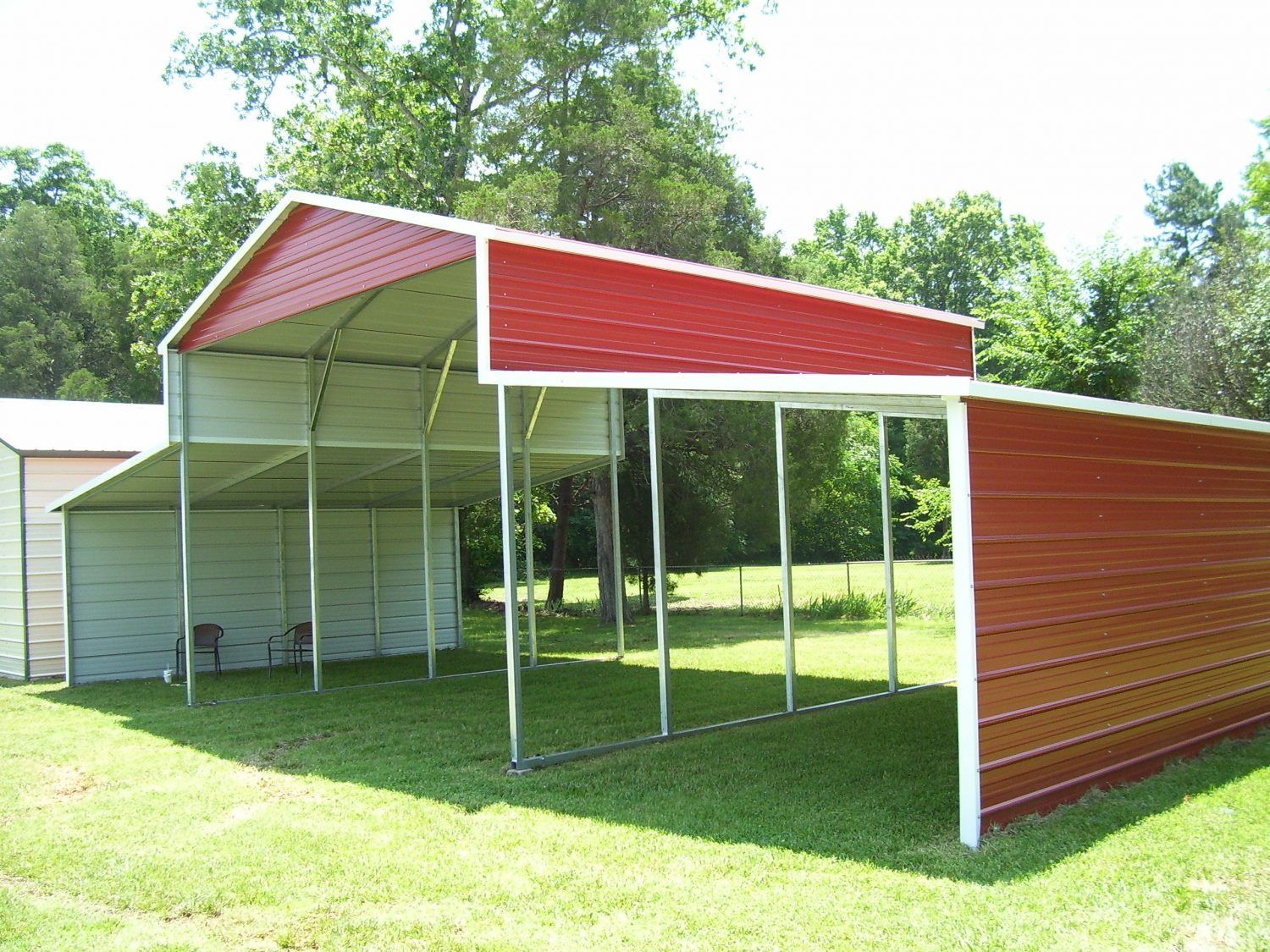 A red and white barn is sitting in the middle of a grassy field.