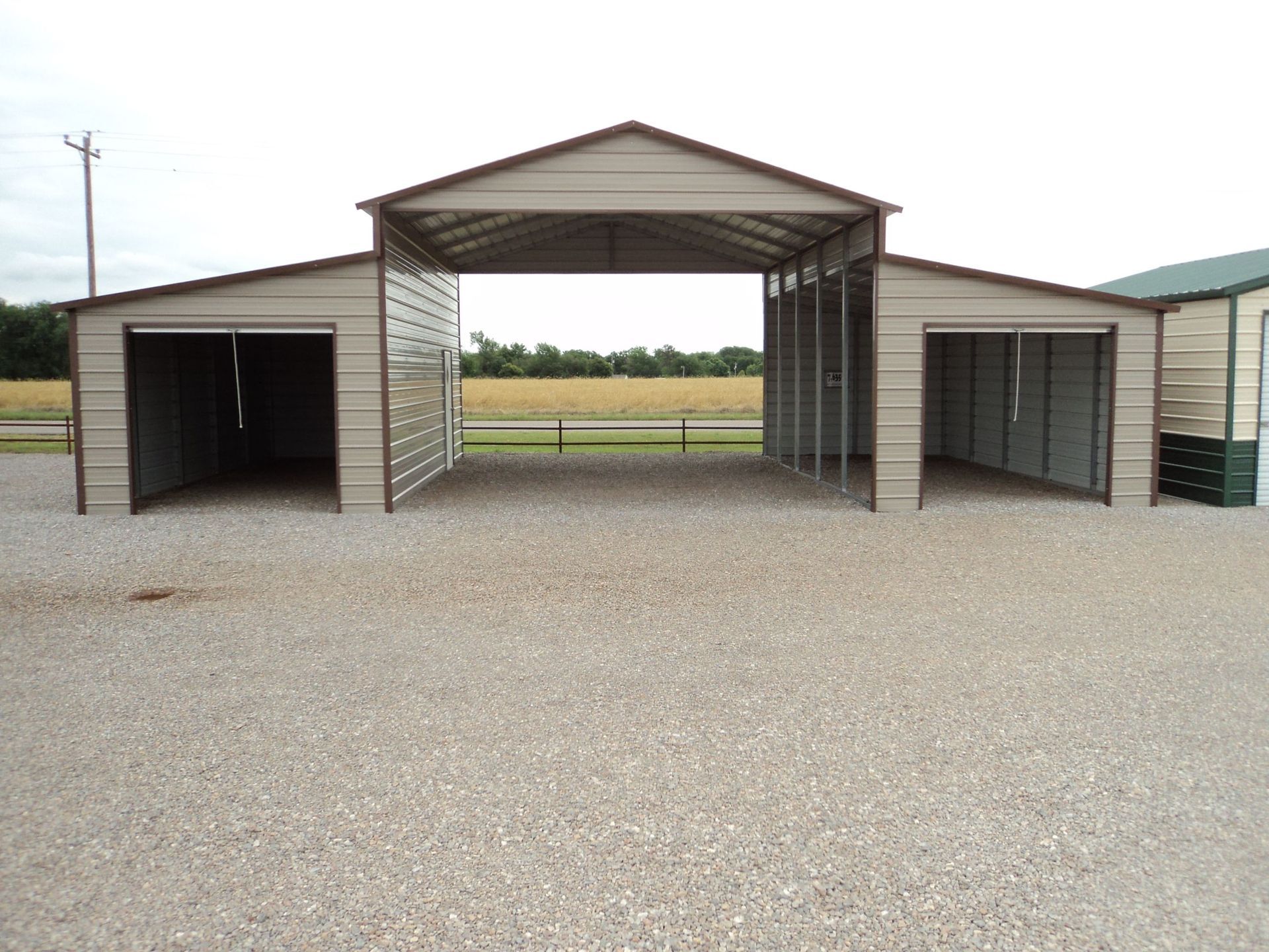 Two metal buildings are sitting in a gravel lot.