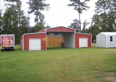 A red truck is parked in front of a red garage