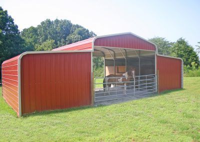 A red barn is sitting in the middle of a grassy field.