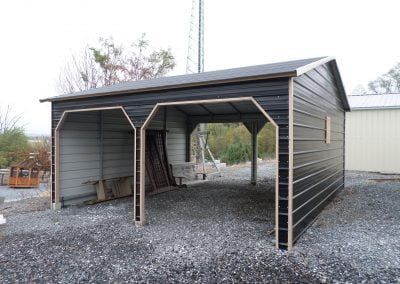 A black garage with two doors is sitting on top of a gravel lot.