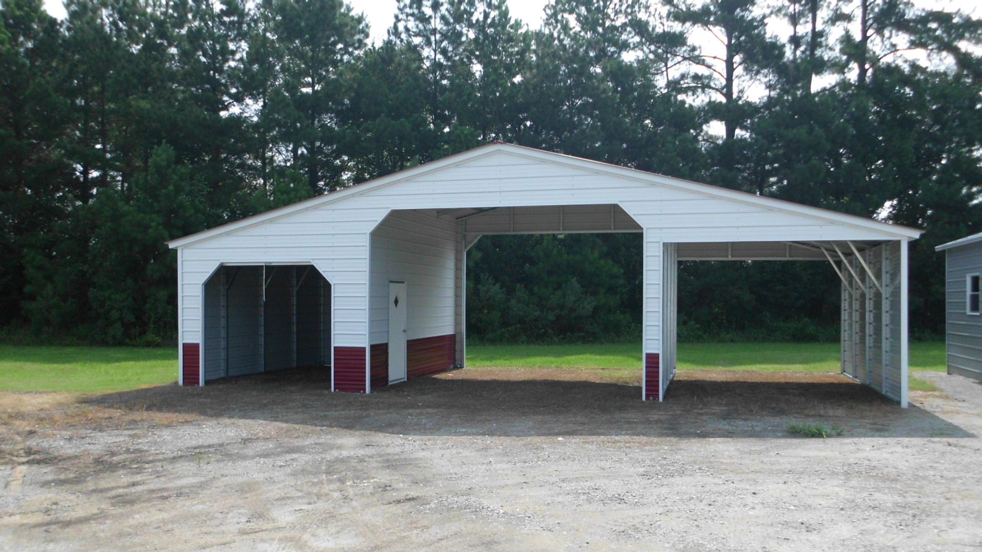A white building with red trim sits in the middle of a dirt field