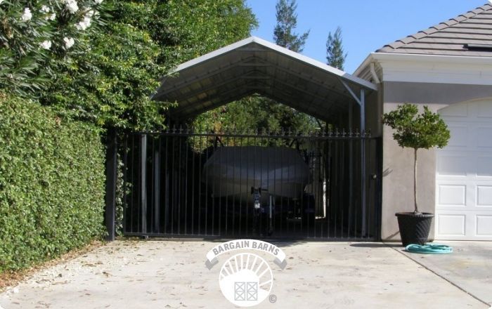 A car is parked under a carport in front of a house.