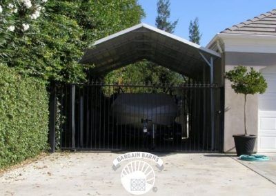 A car is parked under a carport in front of a house