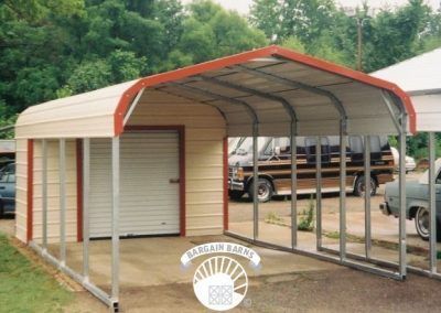 A carport with a red and white roof is sitting next to a garage.