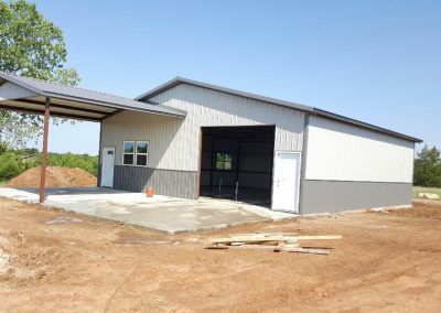 A large metal building is being built in a dirt field.