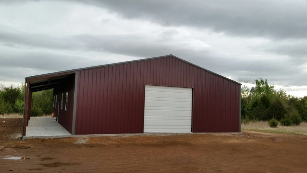 A red metal building with a white garage door and a porch.