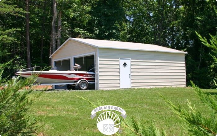 A boat is parked in a garage with trees in the background.