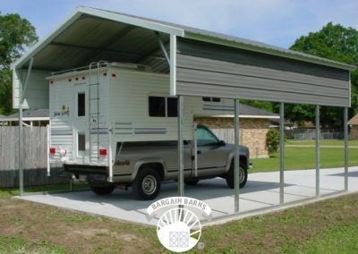 A truck is parked under a carport with a camper on top of it