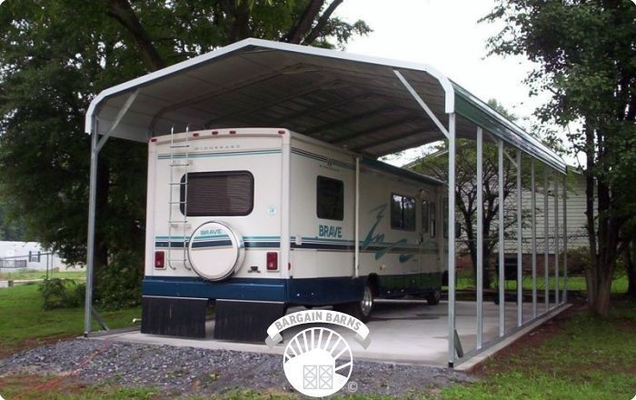 A white and blue rv is parked under a carport