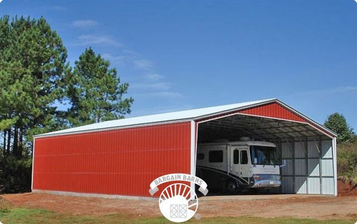 A rv is parked inside of a red barn.