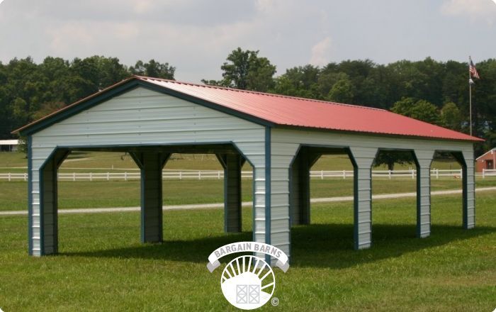 A white building with a red roof is in the middle of a grassy field