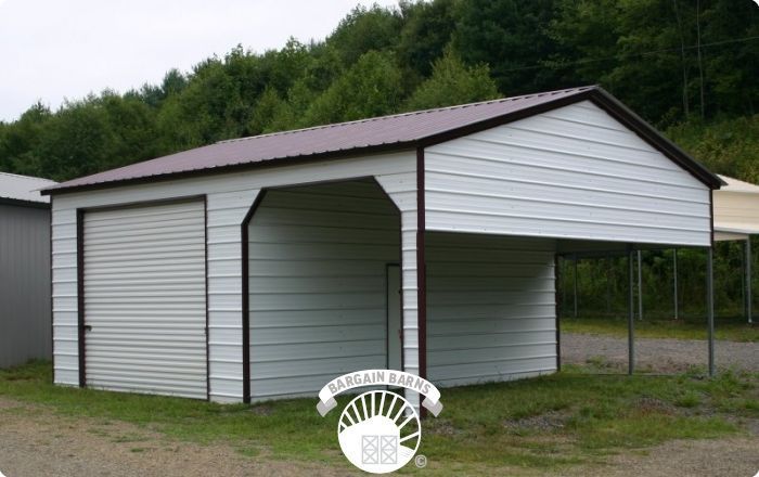 A white garage with a brown roof is sitting in the grass.