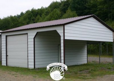 A white garage with a brown roof is sitting in the grass.