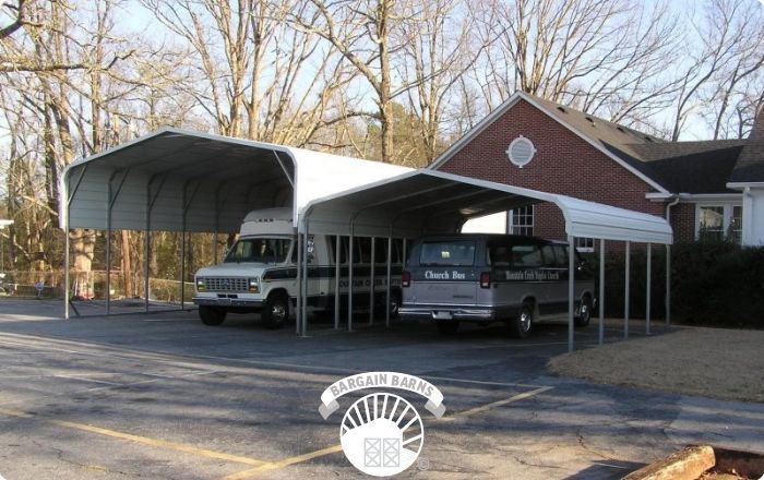 A white van is parked under a canopy in front of a house