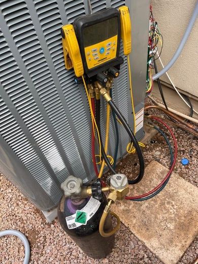 An air conditioner is being serviced with a digital gauge attached to it.