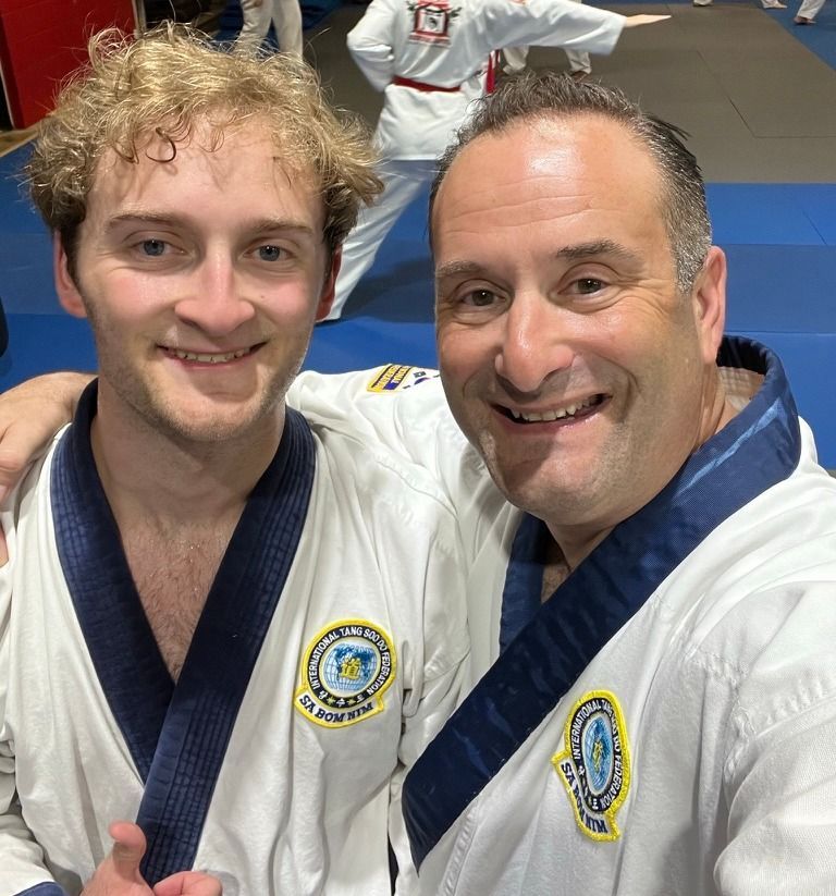 Two men are posing for a picture and one has the number 15 on his shirt