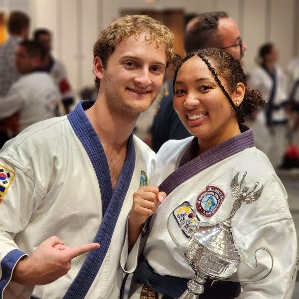 A man and a woman in martial arts uniforms pose for a picture