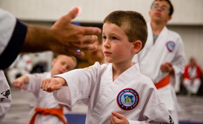 A group of young boys are practicing karate in a gym.