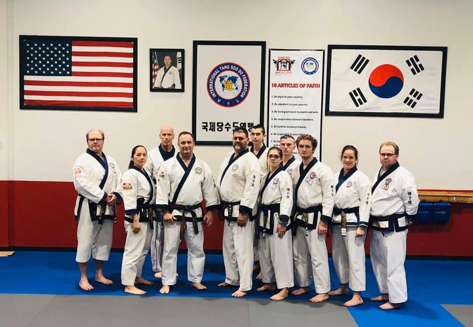 A group of people in karate uniforms are posing for a picture in a gym.