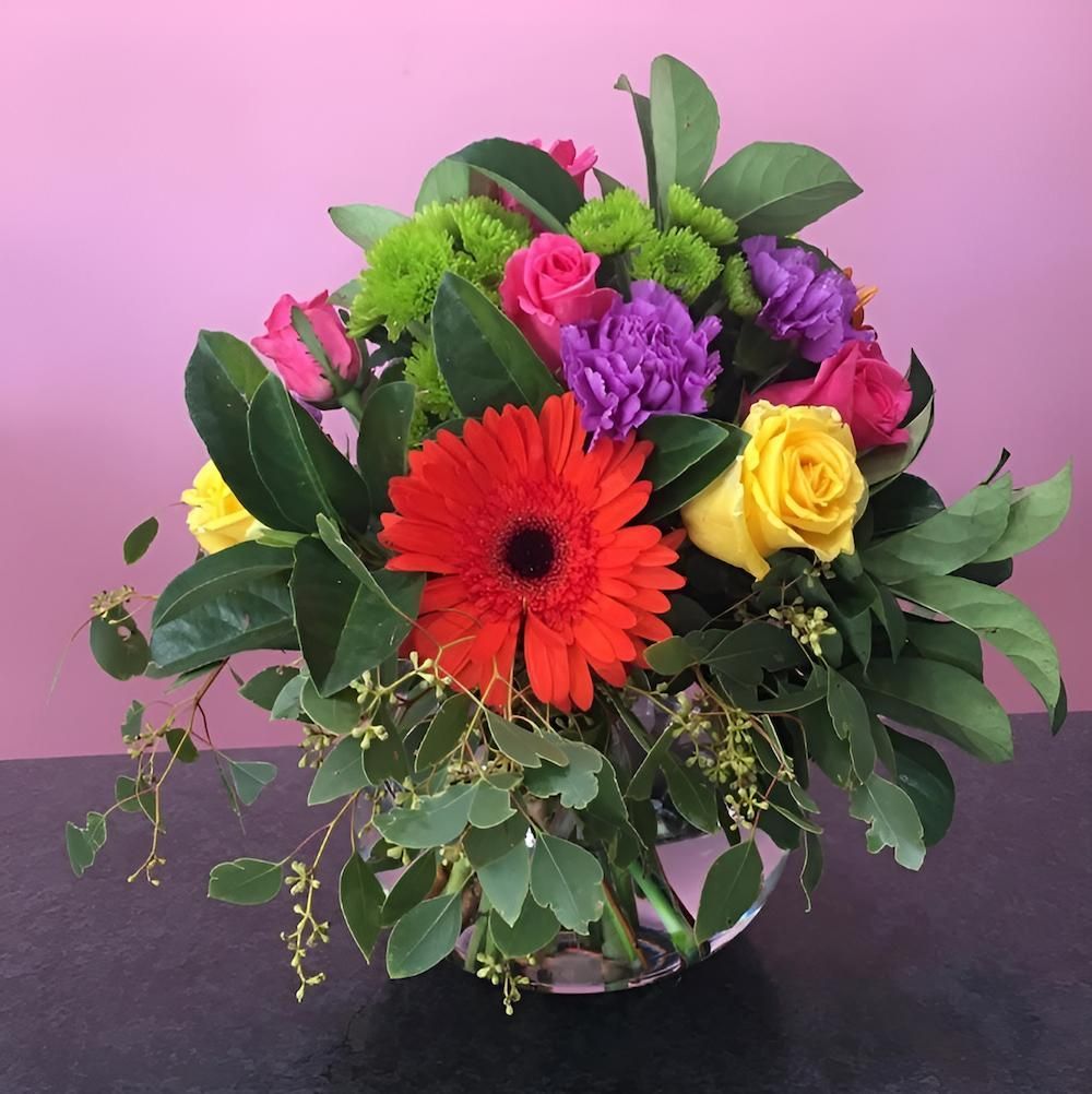 A Vase Filled With Flowers and Greenery on a Table — Bundaberg House of Flowers In Moore Park Beach, QLD