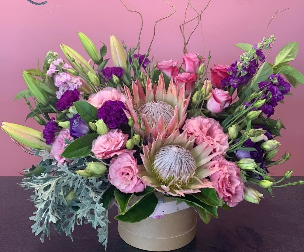 A Vase Filled With Pink and Purple Flowers is Sitting on a Table — Bundaberg House of Flowers In Bargara, QLD