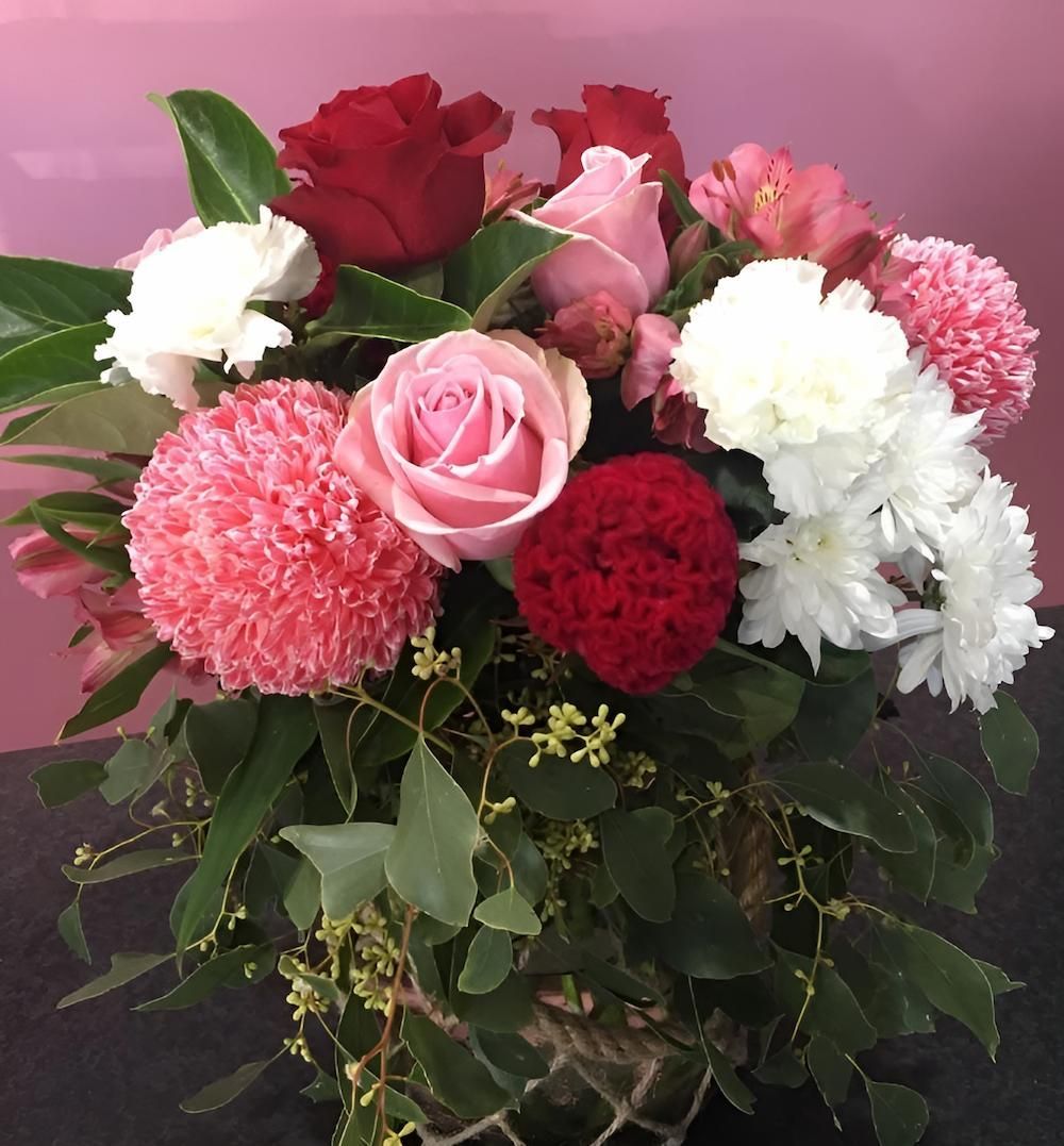 A Vase Filled With Pink and Red Flowers on a Table — Bundaberg House of Flowers In Coral Cove, QLD